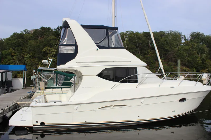 Slide: The Image of 2007 Silverton 36 Convertible yacht docked by a forested shoreline. - 4