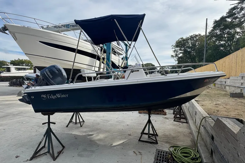 The Image of 2016 Edgewater 158CS boat on stands, with a Yamaha outboard motor, in a marina setting. - 0