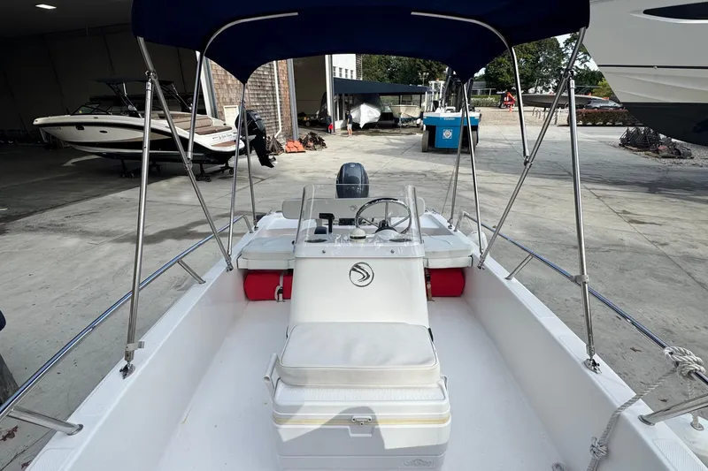 Slide: The Image of 2016 Edgewater 158CS boat with canopy, docked in a marina setting. - 12