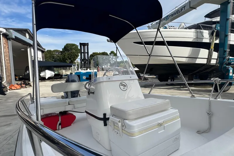Slide: The Image of 2016 Edgewater 158CS boat with canopy, docked near other vessels and equipment. - 16