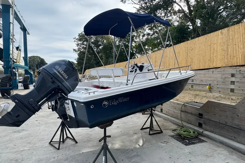 Slide: The Image of 2016 Edgewater 158CS boat with Yamaha motor on stands, blue hull, outdoor setting. - 2