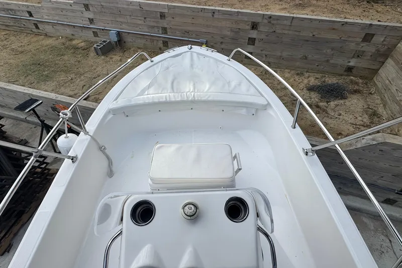 Slide: The Image of 2016 Edgewater 158CS boat interior with seating and storage, docked near wooden barriers. - 21