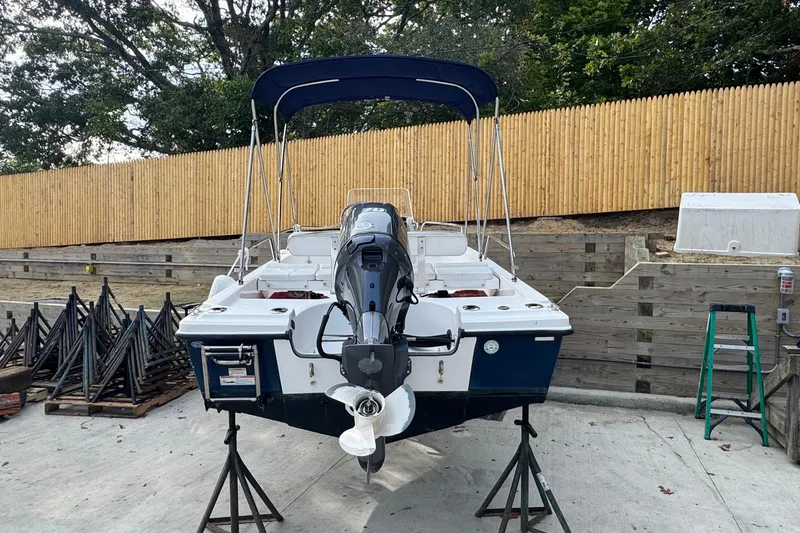 Slide: The Image of 2016 Edgewater 158CS boat on stands, with outboard motor and canopy, in a yard. - 3