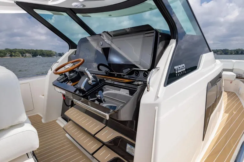 Slide: The Image of 2026 Tiara Yachts 39 helm with modern controls and wooden steering wheel on open water. - 26