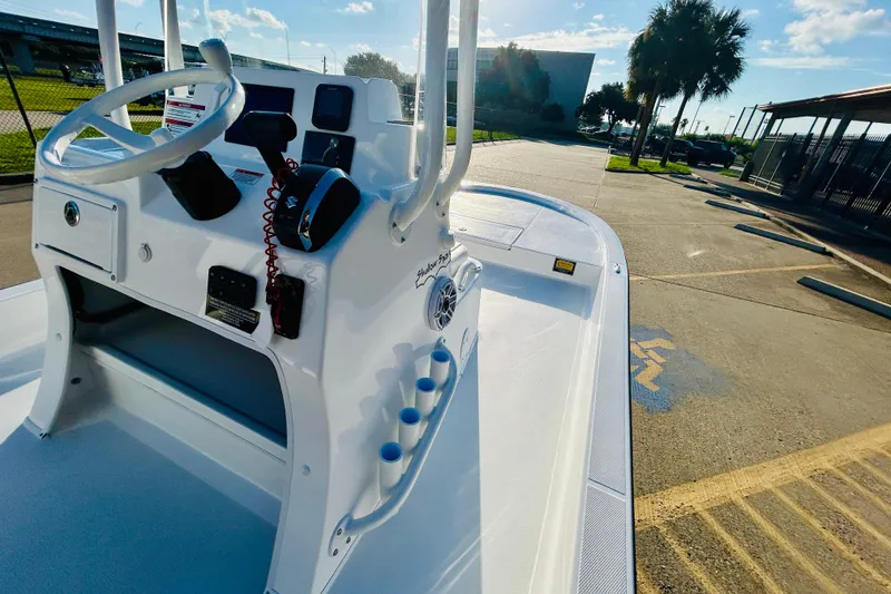 Slide: The Image of 2026 Shallow Sport 18 Sport boat with steering console, parked outdoors under sunny skies. - 10