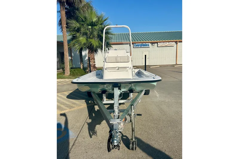 Slide: The Image of 2026 Shallow Sport 18 Sport boat on trailer, parked near palm trees and building. - 2