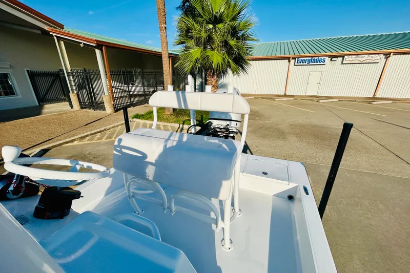 Slide: The Image of 2026 Shallow Sport 18 Sport boat with white seating, parked near a building. - 7