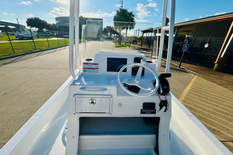 Slide: The Image of 2026 Shallow Sport 18 Sport boat dashboard with steering wheel and controls, parked outdoors. - 8
