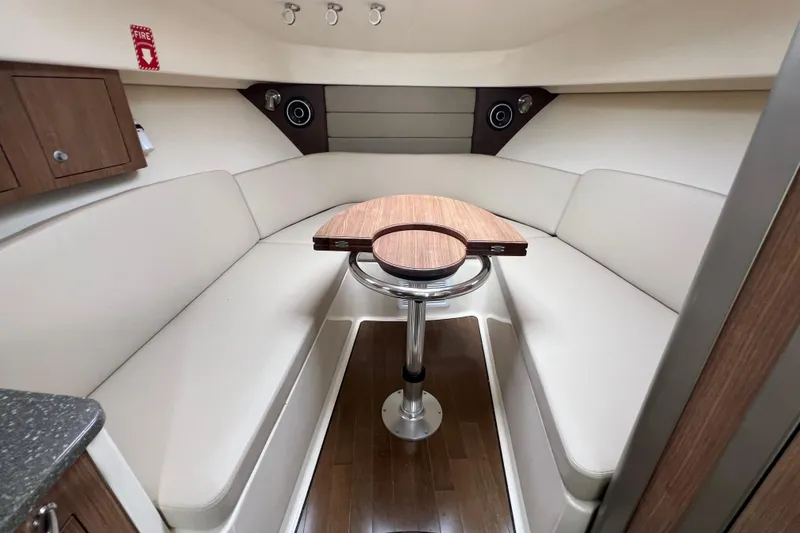 Slide: The Image of 2019 Boston Whaler 315 Conquest cabin interior with seating and wooden table. - 10