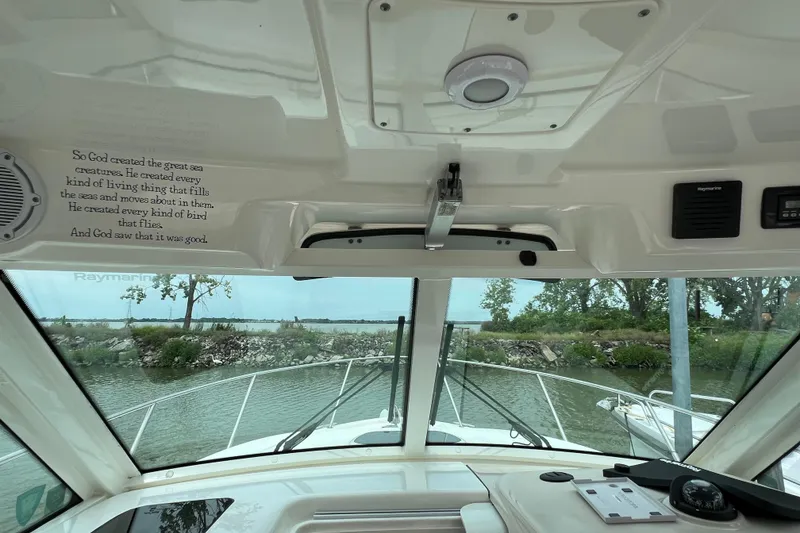 Slide: The Image of 2019 Boston Whaler 315 Conquest helm view with windshield and nature scenery. - 14