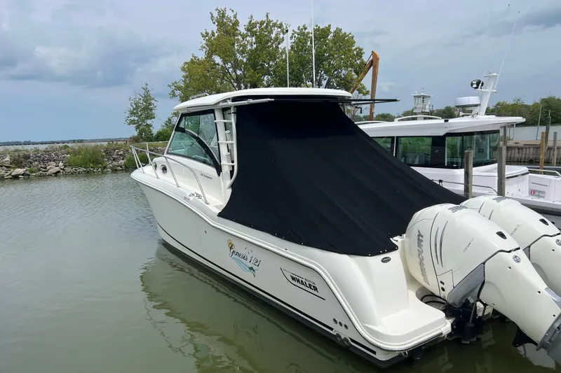 Slide: The Image of 2019 Boston Whaler 315 Conquest boat docked with black cover and twin engines. - 15