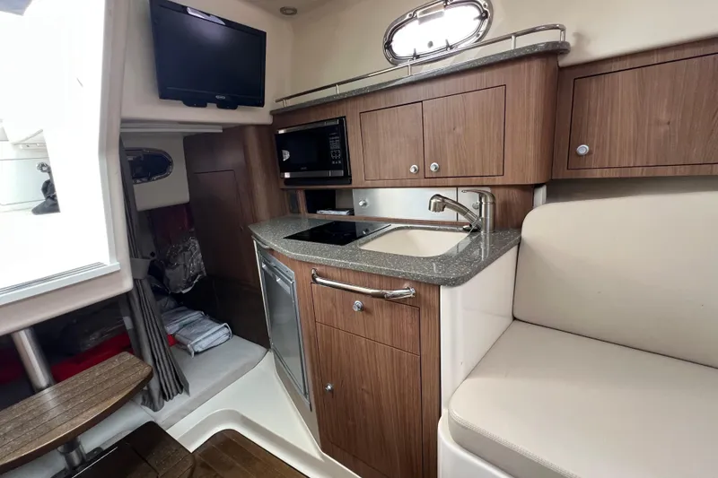 Slide: The Image of 2019 Boston Whaler 315 Conquest interior with kitchenette, TV, and seating area. - 16