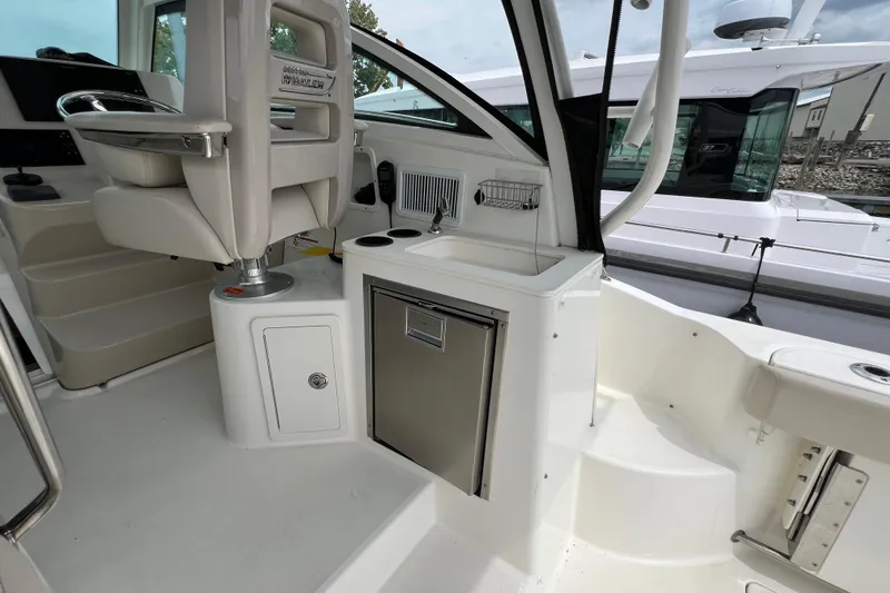 Slide: The Image of 2019 Boston Whaler 315 Conquest cockpit with helm seat and compact kitchenette. - 5