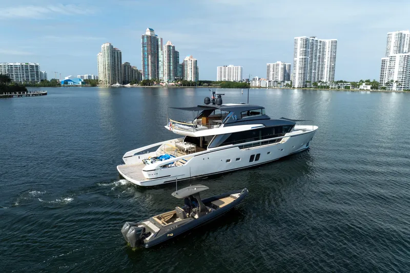 Slide: The Image of Sanlorenzo SX88 2020 yacht cruising near city skyline, accompanied by a smaller boat. - 13