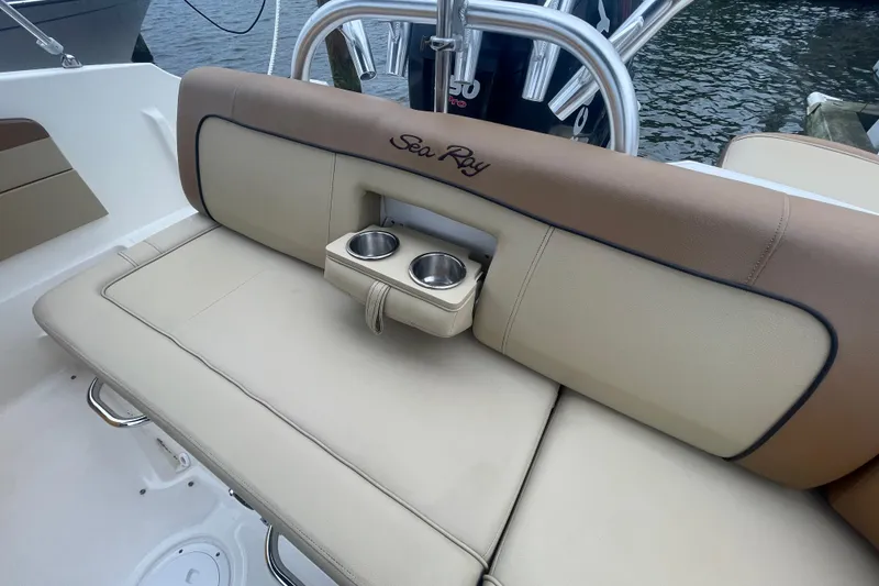 Slide: The Image of 2014 Sea Ray 240 Sundeck Outboard boat seating with cup holders, docked by water. - 12
