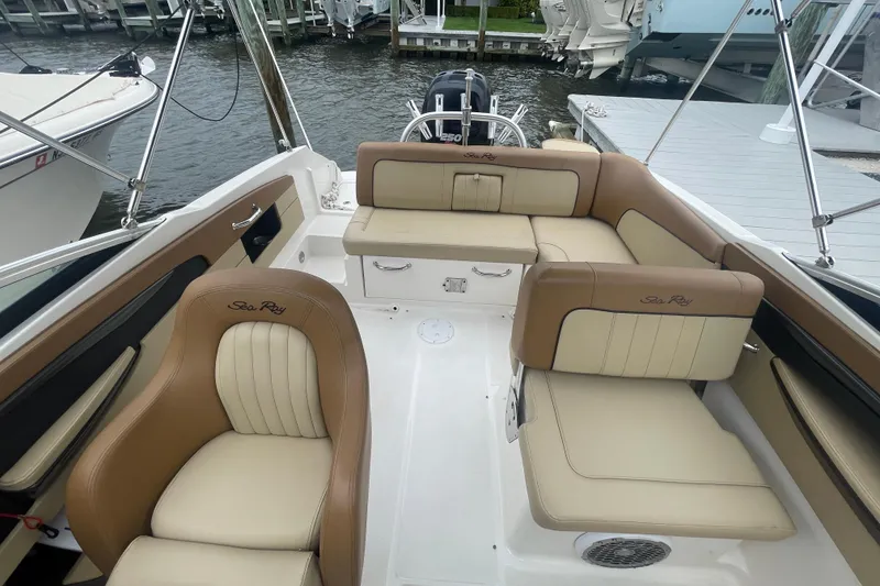 Slide: The Image of 2014 Sea Ray 240 Sundeck Outboard with beige seating, docked by the water. - 4