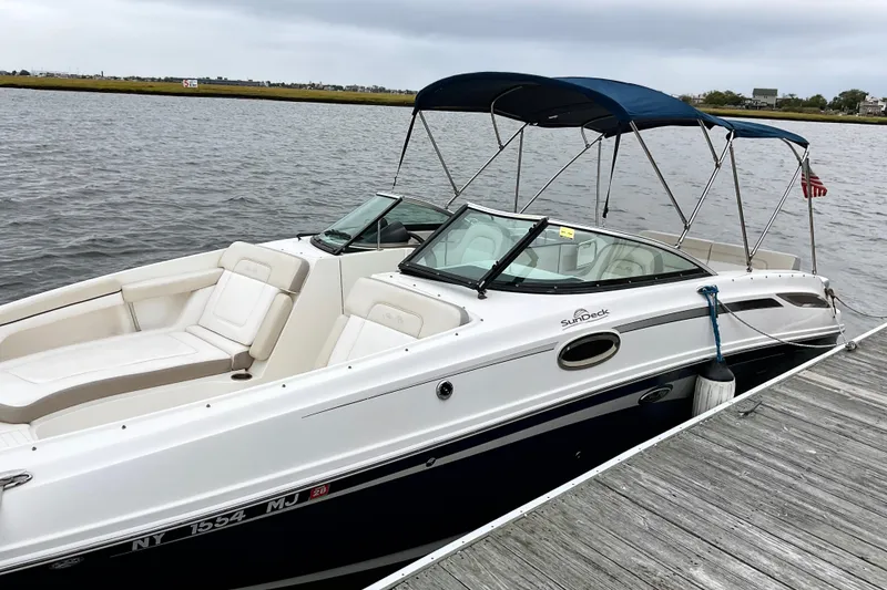 The Image of 2013 Sea Ray 280 Sundeck boat docked by the water, featuring a blue canopy. - 0