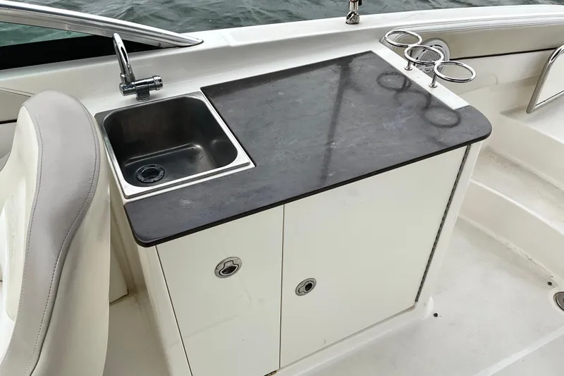 Slide: The Image of 2013 Sea Ray 280 Sundeck boat kitchenette with sink and storage cabinets. - 13