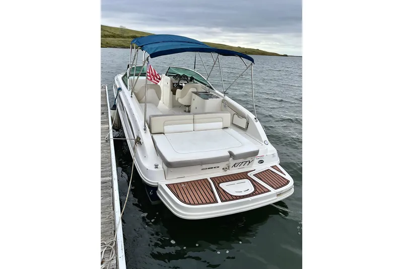 Slide: The Image of 2013 Sea Ray 280 Sundeck boat docked, featuring a blue canopy and spacious seating. - 2