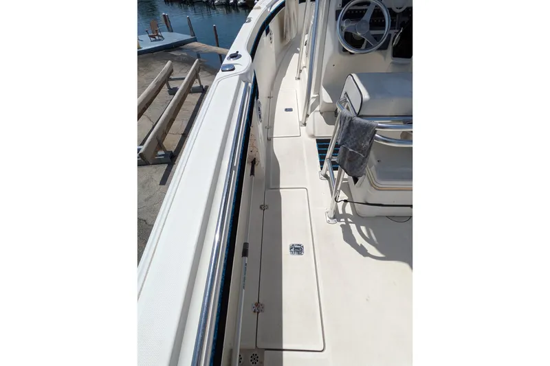 Slide: The Image of 2004 Wellcraft 29 CCF boat interior with steering wheel and seating, docked by the water. - 2