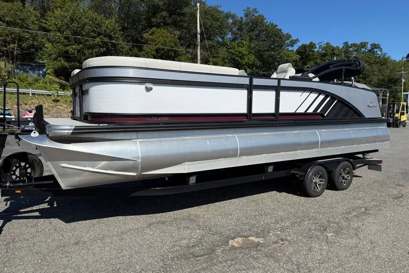 The Image of 2025 Qwest Splash Pad L-Class pontoon boat on trailer, parked outdoors. - 0