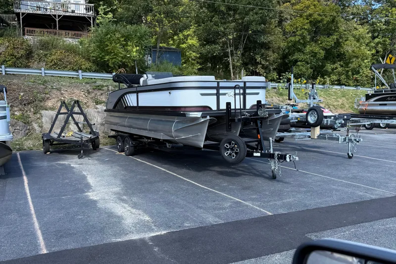 Slide: The Image of 2025 Qwest Splash Pad L-Class pontoon boat on trailer in parking lot. - 2