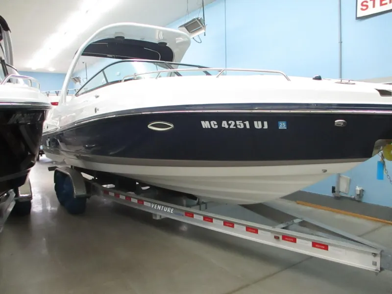 Slide: The Image of 2018 Rinker QX29 CC boat interior with beige and black seating arrangement. - 1