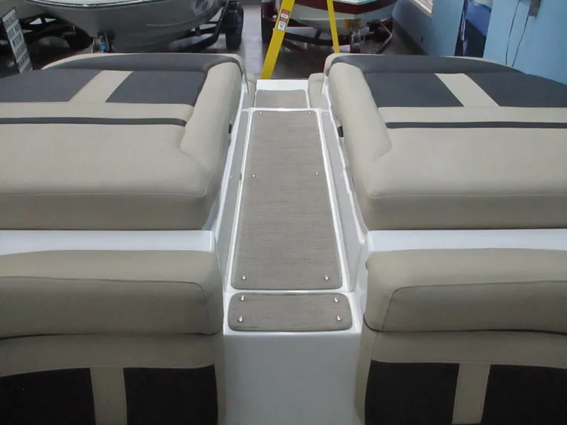 Slide: The Image of 2018 Rinker QX29 CC boat interior with beige and gray cushioned seating. - 14