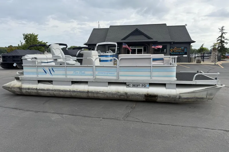 The Image of 1989 Riviera Cruiser Fun Deck 22 pontoon boat parked outside a marina building. - 0