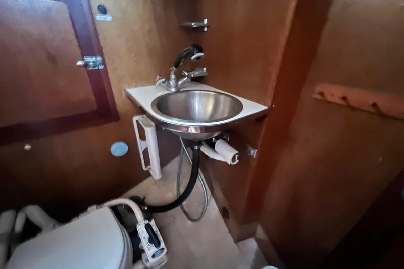 Slide: The Image of Hinckley Pilot 35 Sloop 1964 bathroom with sink and toilet, featuring wooden interior. - 10