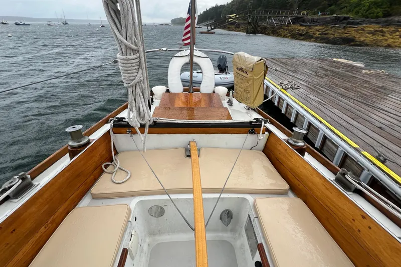 Slide: The Image of 1964 Hinckley Pilot 35 Sloop docked, showcasing wooden deck and seating area. - 20