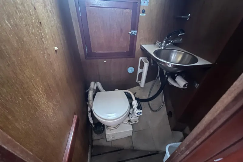 Slide: The Image of 1964 Hinckley Pilot 35 Sloop bathroom with toilet, sink, and wooden cabinetry. - 9