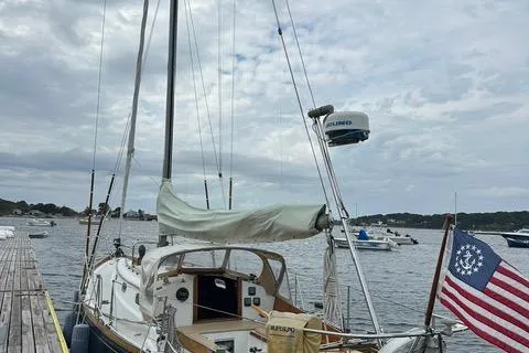 Slide: The Image of Hinckley Pilot 35 Sloop, 1964, docked with American flag, cloudy sky, and calm waters. - 30