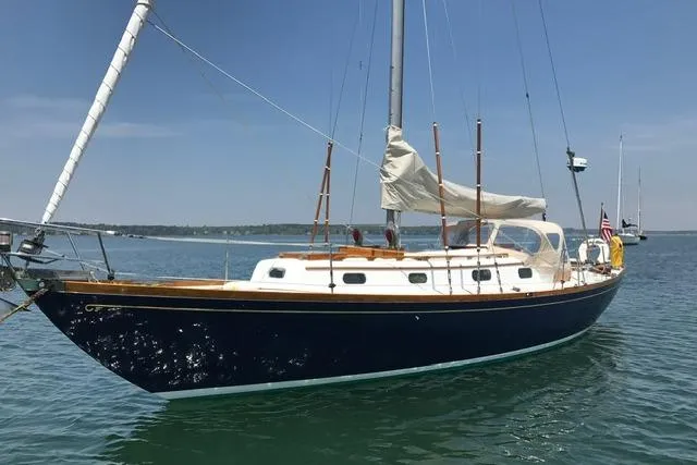 Slide: The Image of 1964 Hinckley Pilot 35 Sloop sailing on calm waters under a clear blue sky. - 33