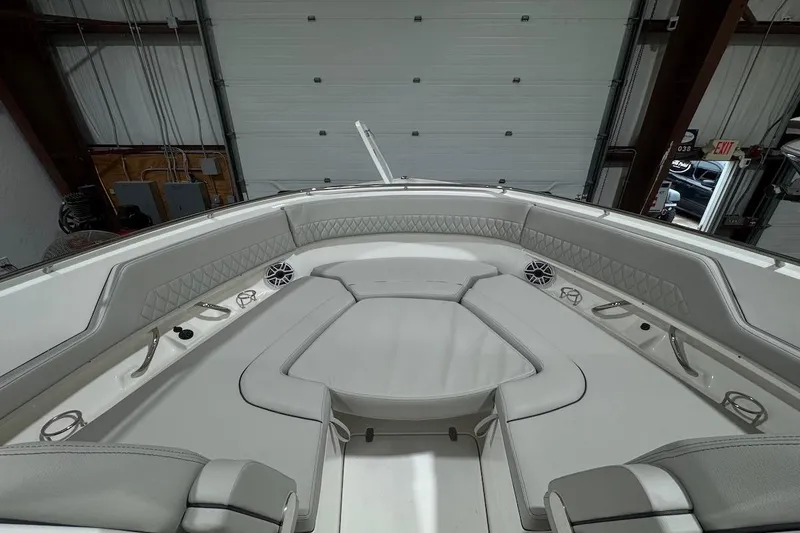 Slide: The Image of 2026 Pursuit DC 326 Dual Console boat interior with cushioned seating and speakers in a garage. - 17