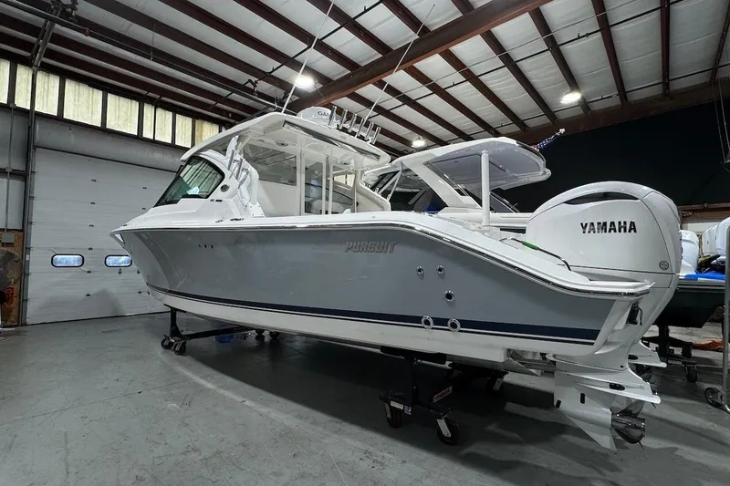 Slide: The Image of 2026 Pursuit DC 326 Dual Console boat in a warehouse, featuring Yamaha engines. - 2