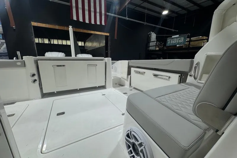 Slide: The Image of 2026 Pursuit DC 326 Dual Console interior with seating and storage, under American flag. - 31