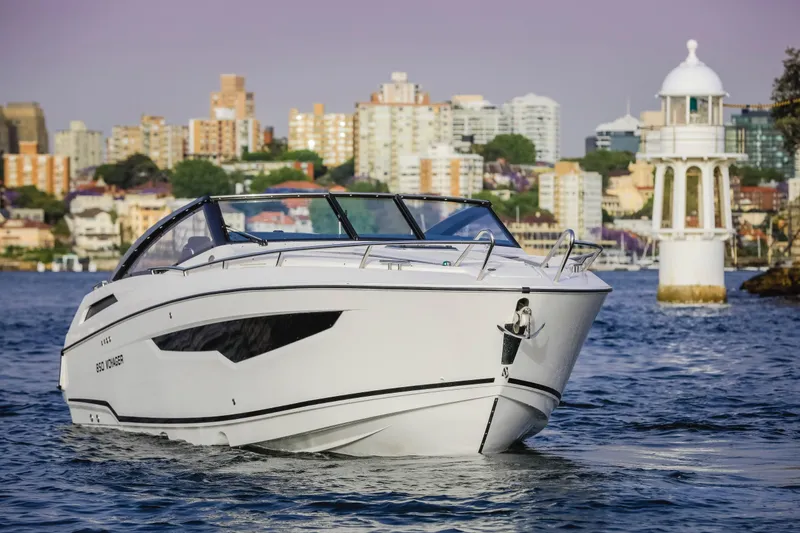 Slide: The Image of 2022 Parker Poland 850 Voyager boat cruising near a lighthouse with cityscape background. - 12