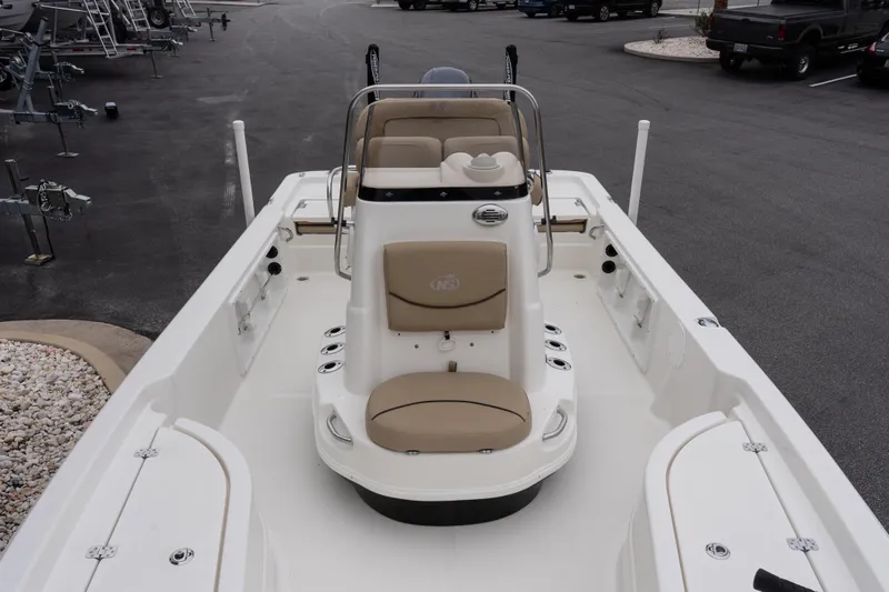 Slide: The Image of 2020 NauticStar 215 XTS boat interior with beige seating and console, parked on asphalt. - 13