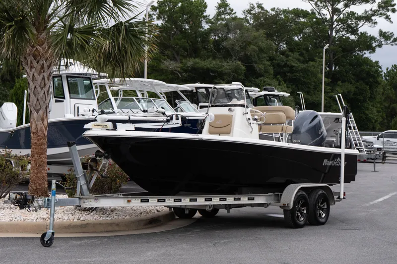 Slide: The Image of 2020 NauticStar 215 XTS boat on trailer, parked near palm tree. - 2