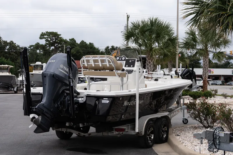 Slide: The Image of 2020 NauticStar 215 XTS boat on trailer, parked near palm trees. - 6