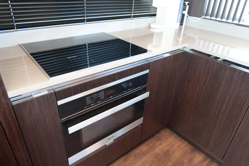 Slide: The Image of Modern kitchen with sleek appliances, dark wood cabinets, and a Pearl 62 model cooktop. - 14