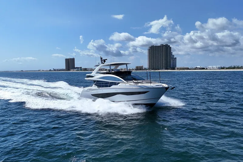 Slide: The Image of Luxury Pearl 62 yacht cruising on open water, 2022 model, with city skyline backdrop. - 73