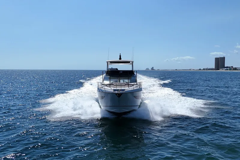 Slide: The Image of 2022 Pearl 62 yacht cruising on open sea with city skyline in background. - 74