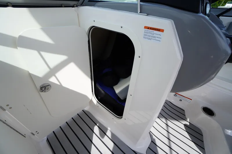 Slide: The Image of 2022 Chaparral 23 SSi OB boat storage compartment with open door on striped deck. - 20