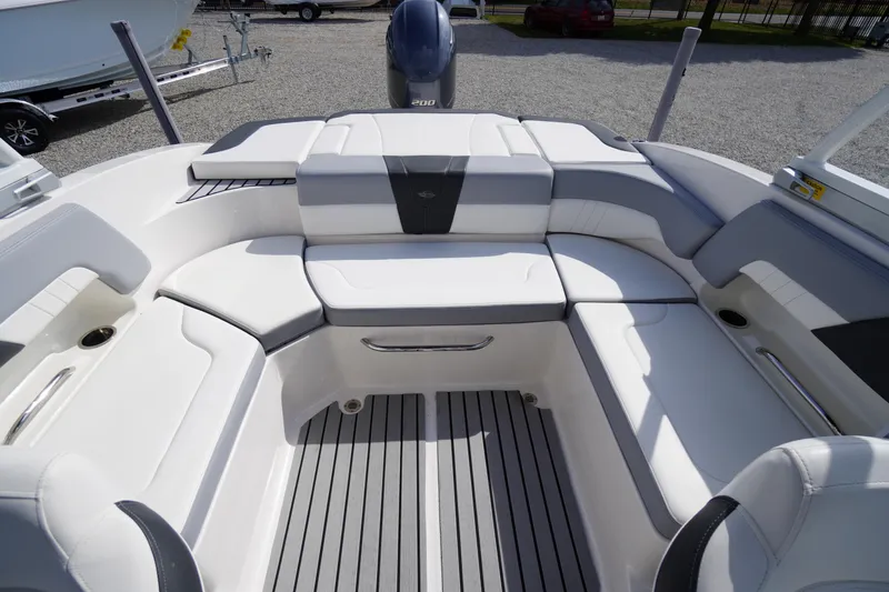 Slide: The Image of 2022 Chaparral 23 SSi OB boat interior with white cushioned seating and gray flooring. - 24
