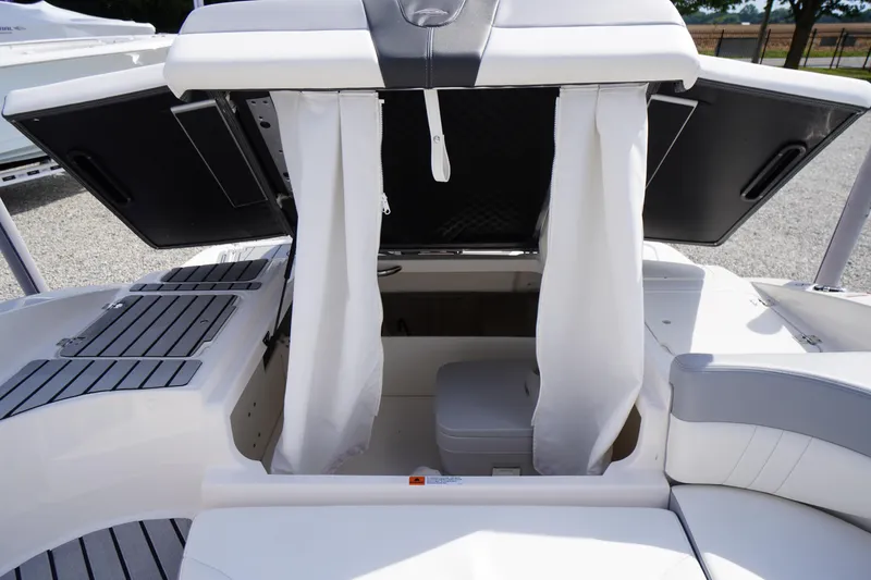 Slide: The Image of 2022 Chaparral 23 SSi OB boat interior with open storage compartment and white curtains. - 36