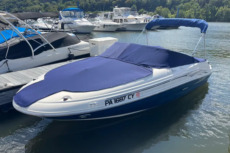 Slide: The Image of 2006 Sea Ray 200 Sundeck boat docked with blue cover, surrounded by other boats. - 7