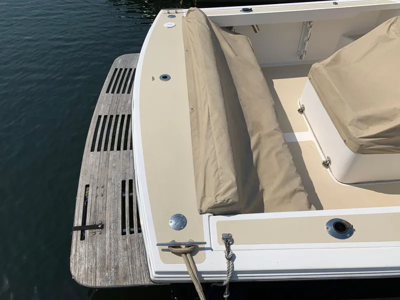 Slide: The Image of 2004 Hunt Yachts Surfhunter 25 boat with beige seating and wooden deck by the water. - 10