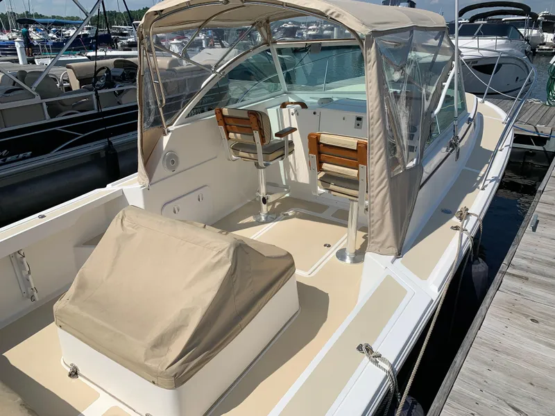 Slide: The Image of 2004 Hunt Yachts Surfhunter 25 with beige canopy and seating, docked at marina. - 11